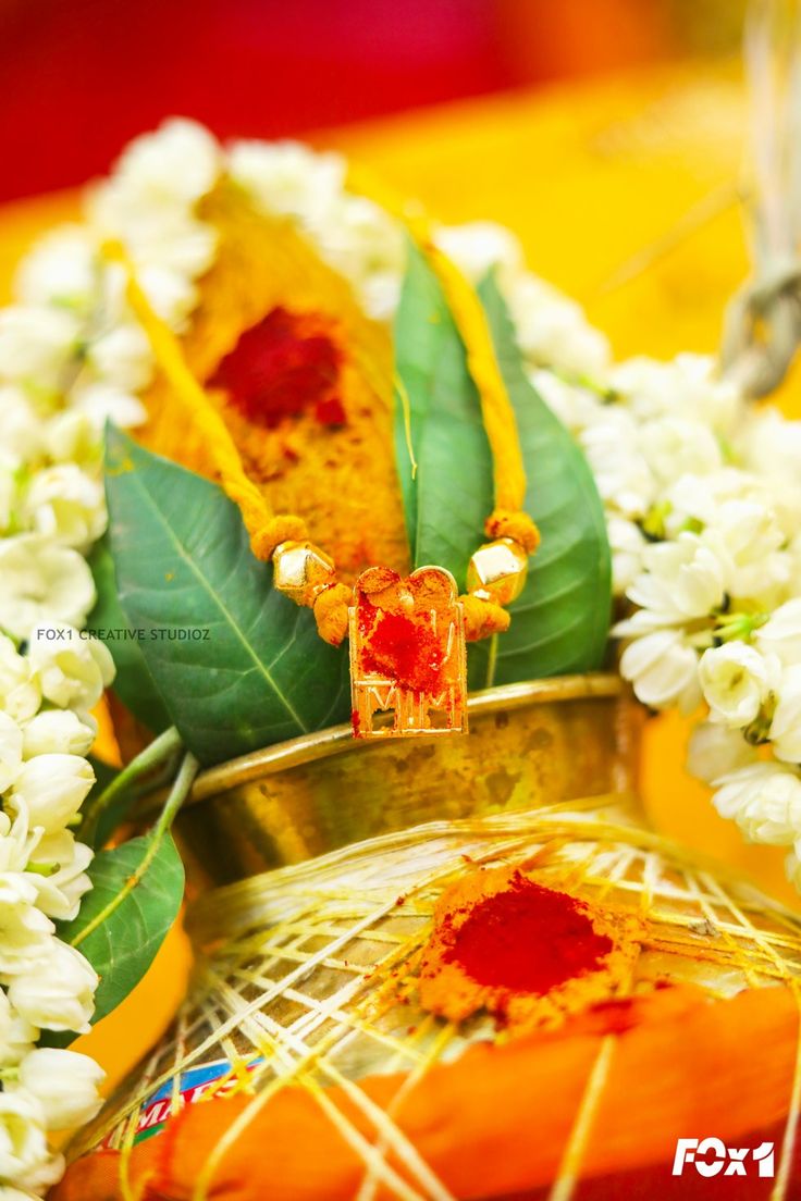 some white flowers and green leaves on a yellow table cloth with red sauce in the center