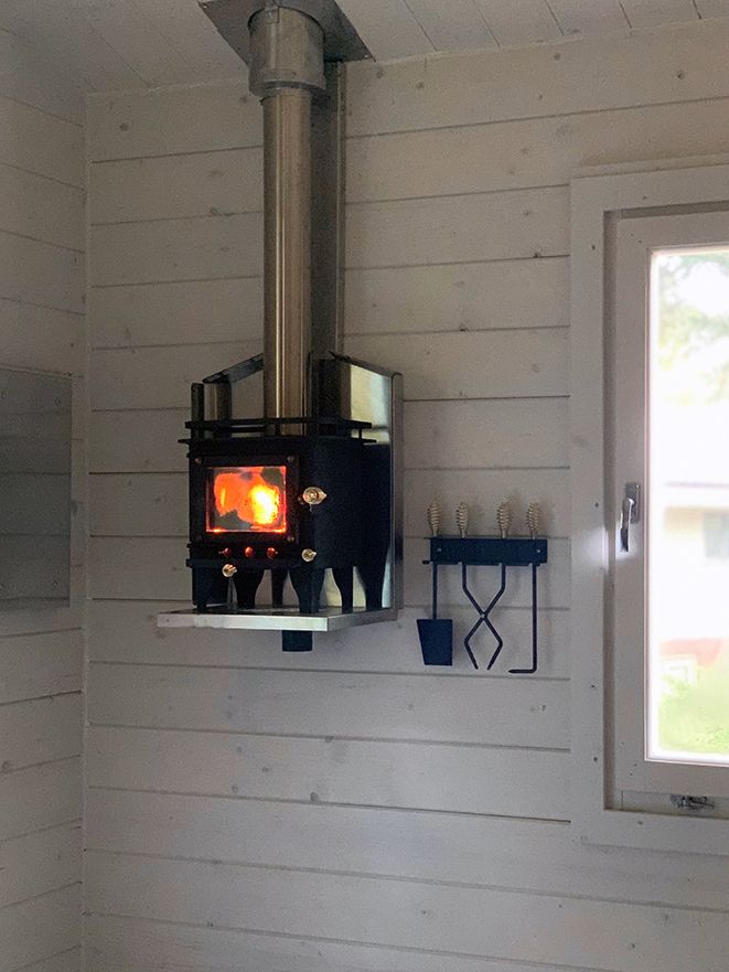 a wood burning stove mounted to the side of a wall in a room with white paneling