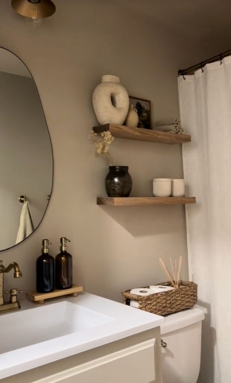 a white toilet sitting next to a bathroom sink under a large mirror above a wooden shelf