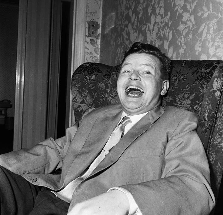 a man in a suit and tie sitting on a chair with his mouth wide open