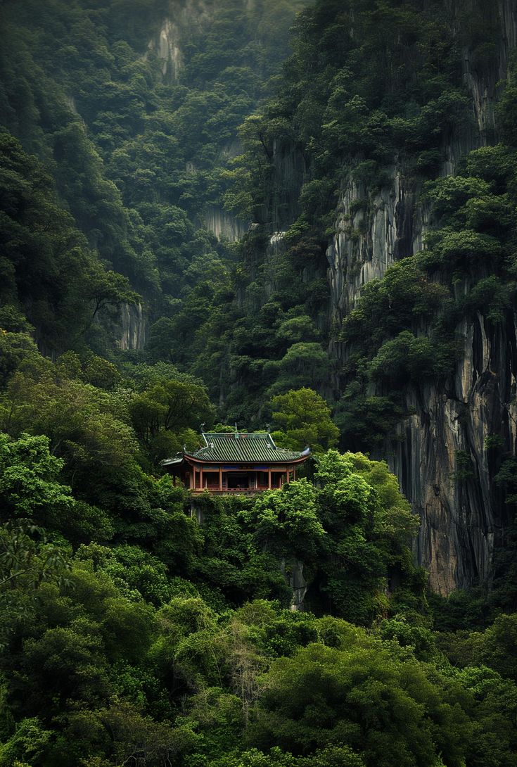 a small building on the side of a mountain surrounded by lush green trees and bushes