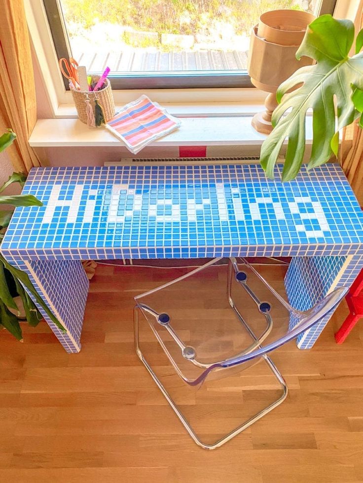 a blue tiled table sitting on top of a wooden floor next to a potted plant