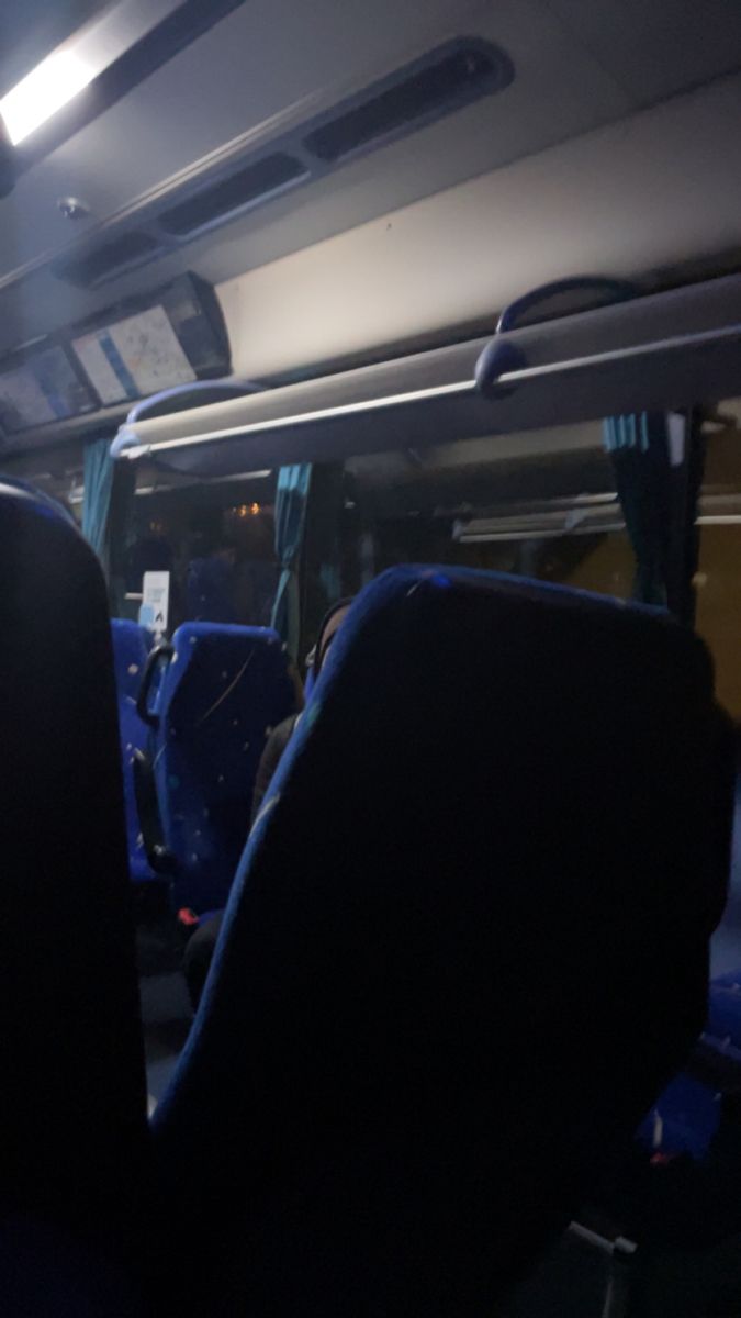 the inside of a bus with blue seats and lights on it's ceiling is empty