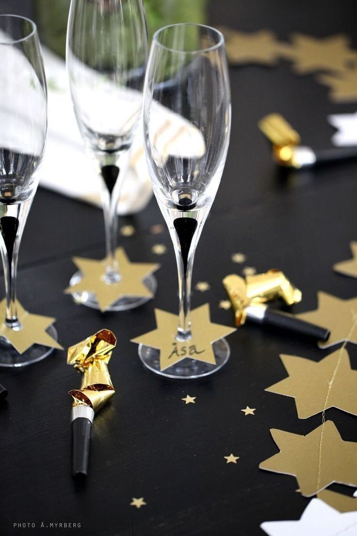 two wine glasses sitting on top of a table next to some confetti sticks