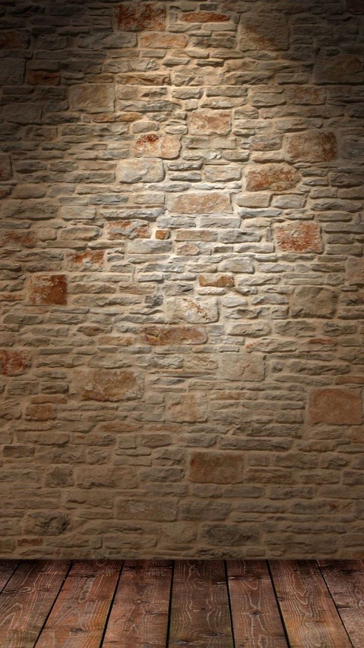 an empty room with brick wall and wood flooring, illuminated by a spot light