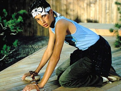 a woman kneeling down on top of a wooden deck next to a tree and bushes