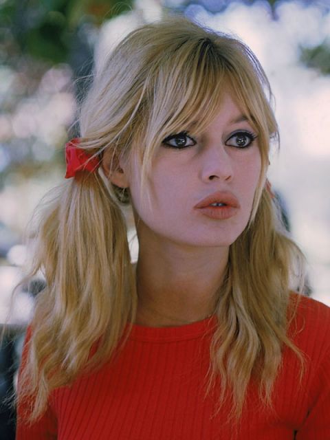 a woman with long blonde hair wearing a red shirt and holding a fork in her hand