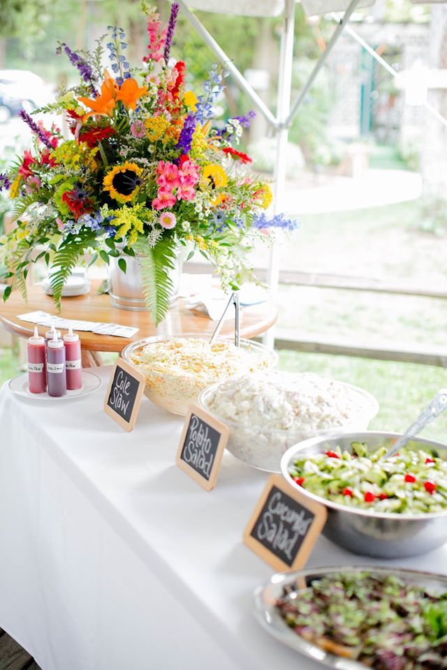 a table topped with lots of food next to a vase filled with different types of flowers