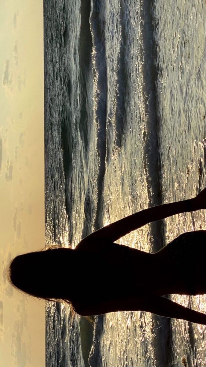 the silhouette of a person standing in front of an ocean view with waves crashing on them