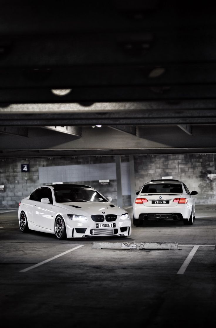 two cars parked in a parking garage next to each other on the street and one is white