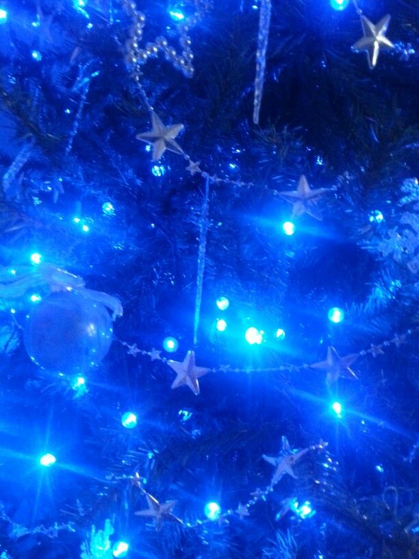 a blue christmas tree with lights and ornaments