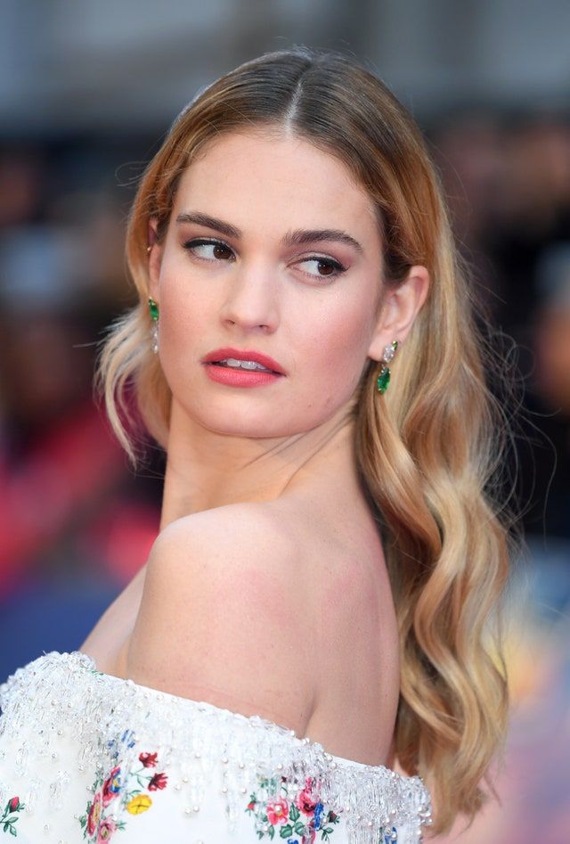 a woman with long blonde hair wearing green earrings and a white dress is looking off to the side