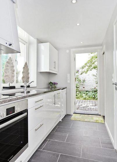 a kitchen with white cabinets and stainless steel appliances, including an open door leading to the outside patio