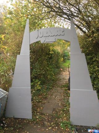 an arch in the middle of a path that has writing on it and is surrounded by trees