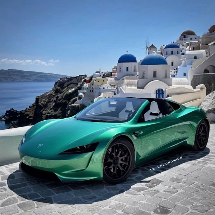 a green sports car parked in front of the ocean