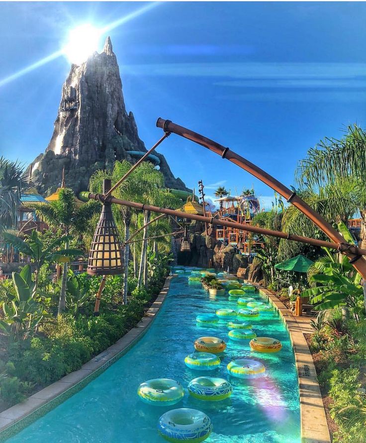 the water slide at universal studios is surrounded by palm trees and other tropical plants, with mountains in the background