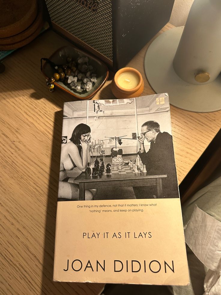 a book sitting on top of a wooden table next to a cup and candle holder