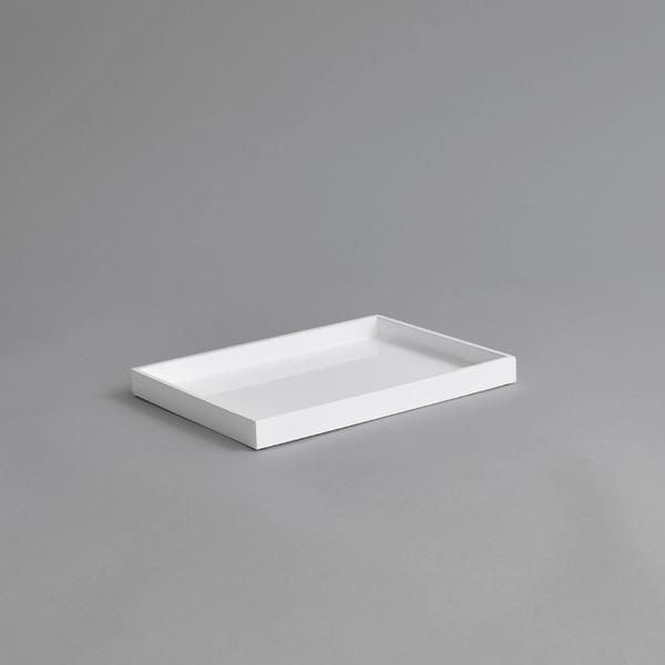 an empty white tray on a gray surface with no one in the photo to describe