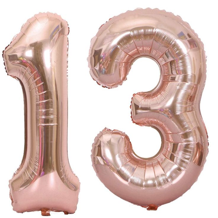 the number thirteen is made out of shiny pink foil balloons and sits in front of a white background