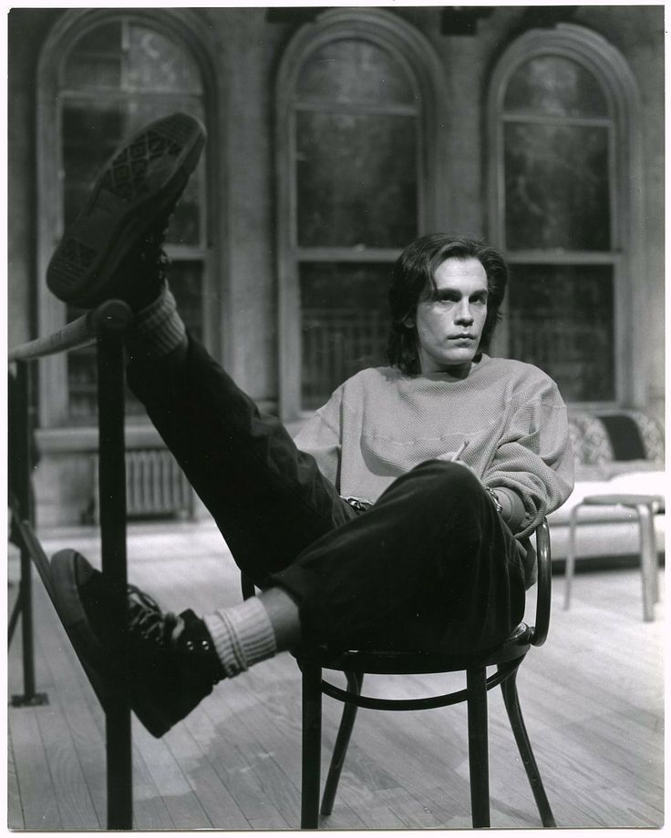 a black and white photo of a man sitting in a chair with his feet up