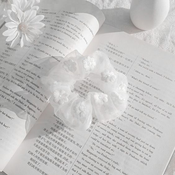 an open book with flowers on top of it next to two eggs and one flower