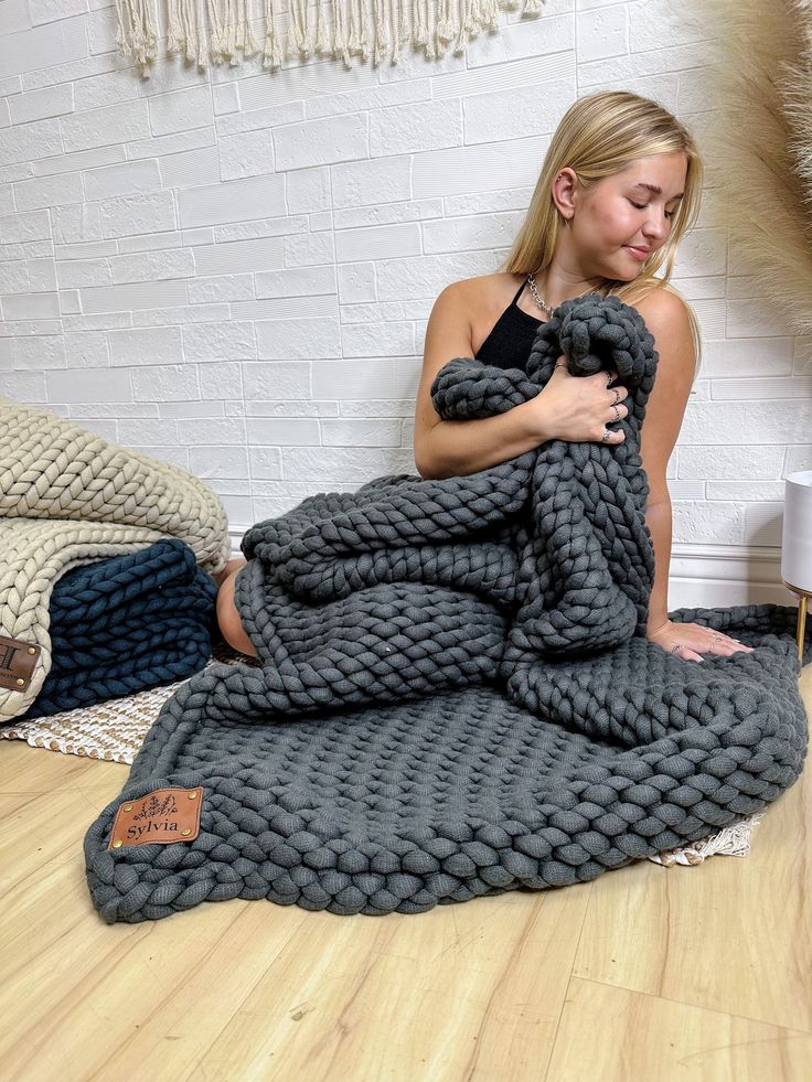 a woman sitting on the floor wrapped in a blanket