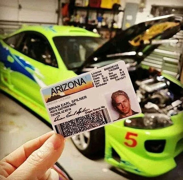 someone holding up a car id card in front of a green sports car with the number 5 on it