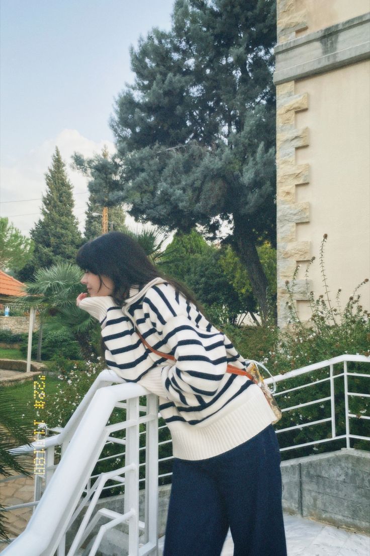 a woman leaning against a railing with her back to the camera