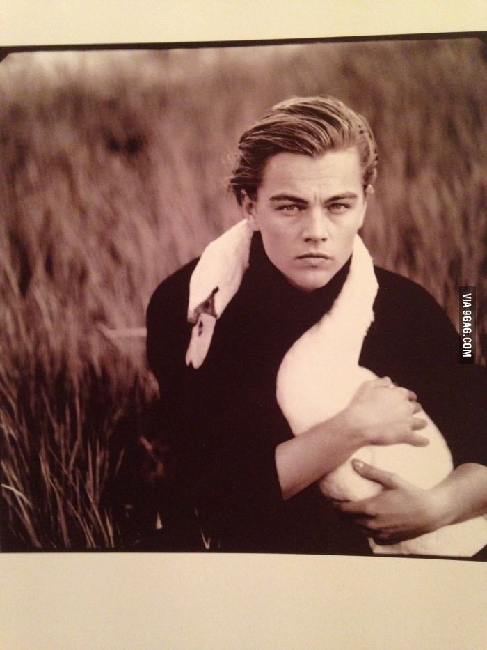 a man holding a baby in his arms while posing for a photo with tall grass behind him