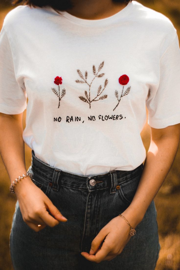 a woman wearing a t - shirt that says no rain, no flowers on it