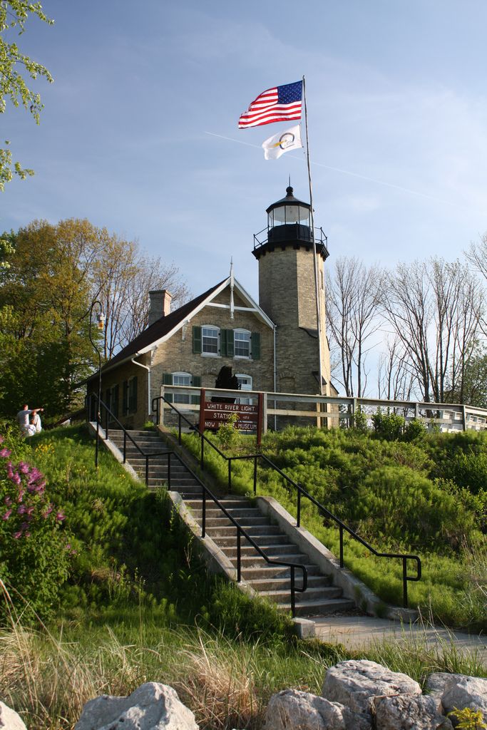 an american flag flying in front of a light house with stairs leading up to it