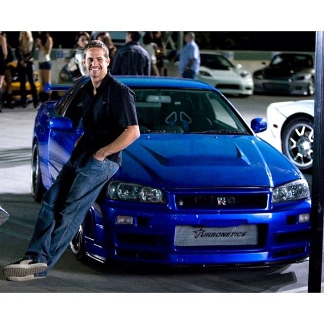 a man leaning on the hood of a blue car