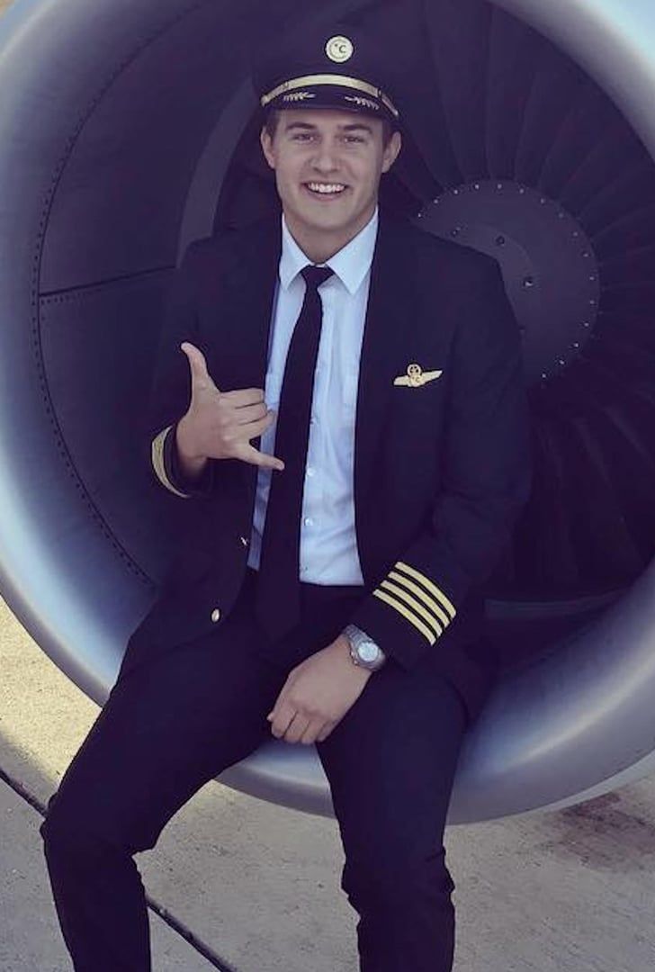 a man in a suit and tie is sitting on an airplane engine with his finger up
