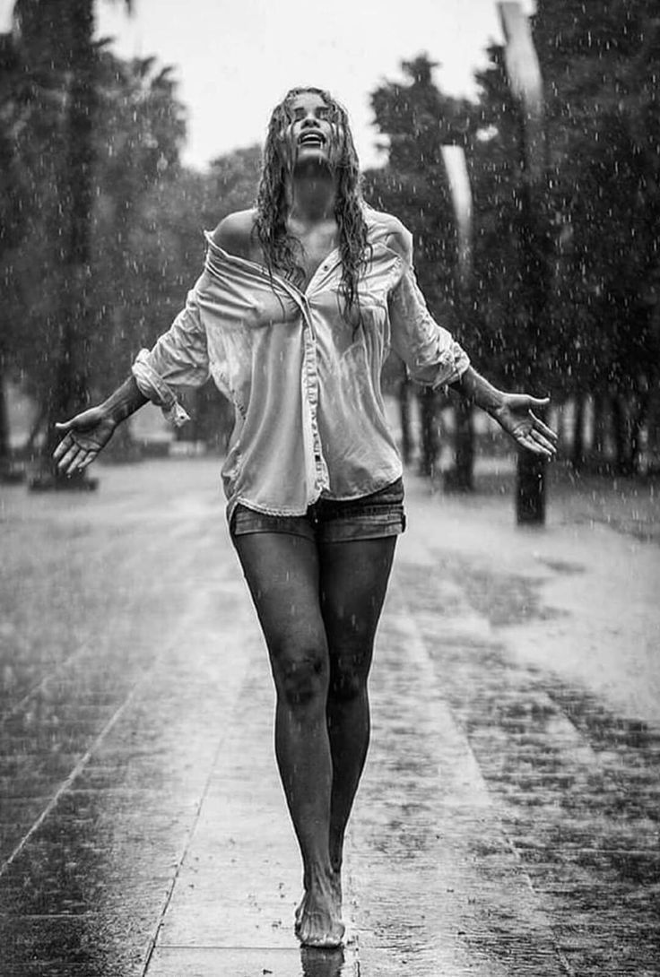 a woman walking in the rain with her arms outstretched