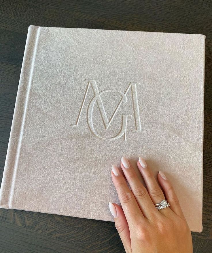 a woman's hand on top of a book with the letter m in it