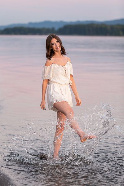 a woman in white dress walking through water