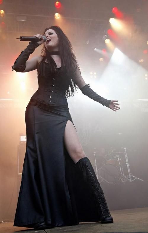 a woman in black dress on stage with microphone