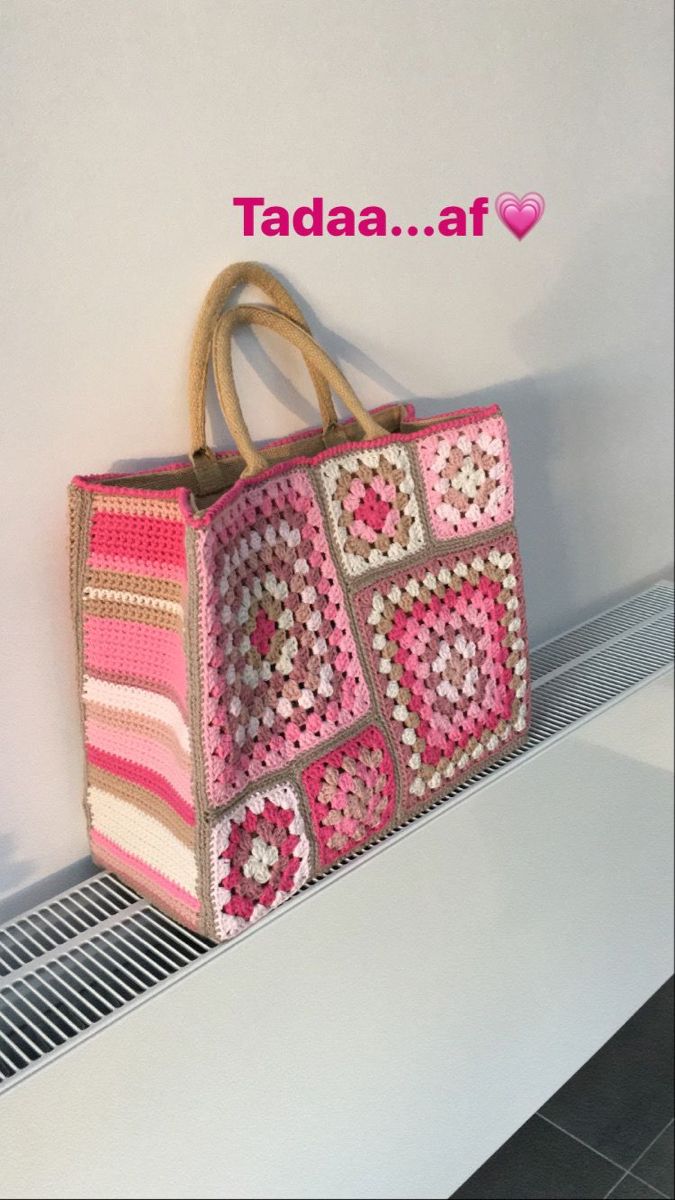 a crocheted pink and white bag sitting on top of a shelf next to a wall