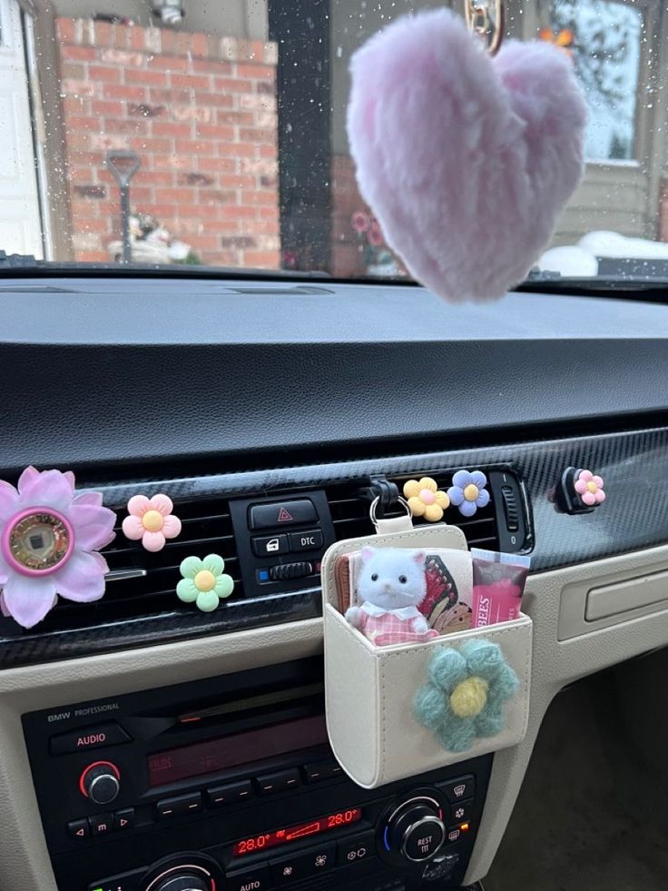 a car dashboard with some stuffed animals in the center console and an air freshener hanging from the dash board