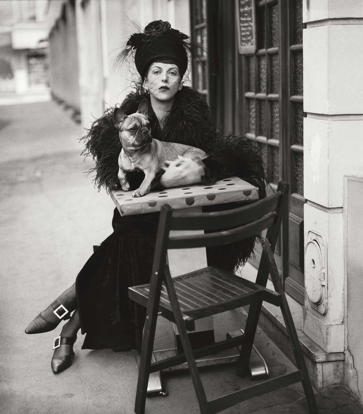 an old photo of a woman sitting on a chair with a dog in her lap