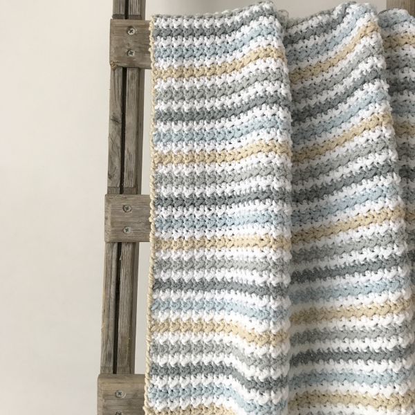 a crocheted blanket hanging from a wooden ladder