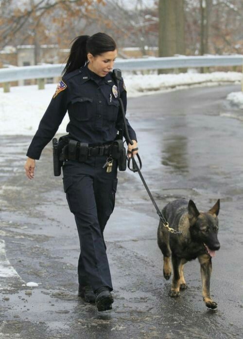 a woman police officer walking her dog in the snow