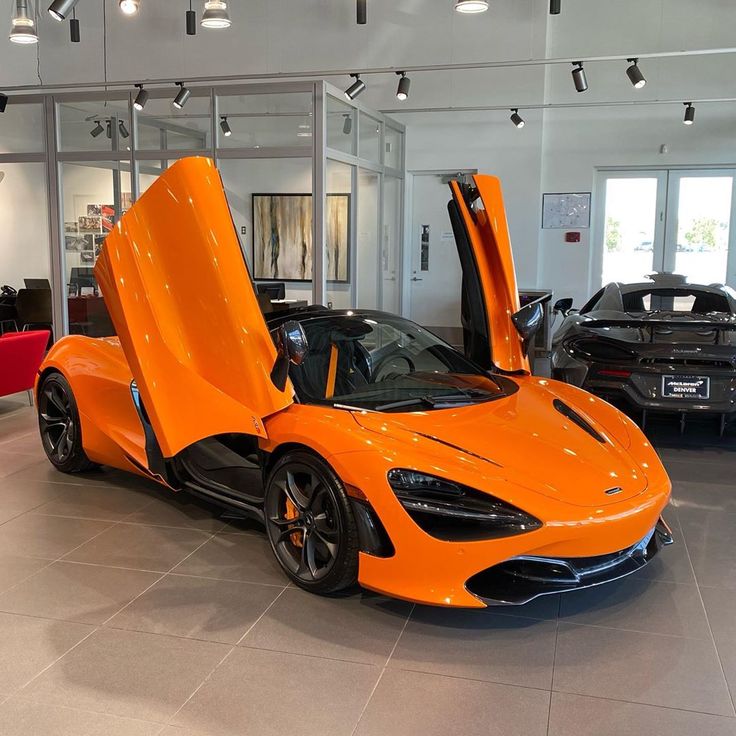an orange sports car in a showroom with its doors open to reveal the interior