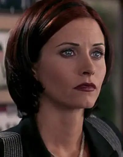 a woman with red hair and blue eyes looking off to the side while wearing a black jacket