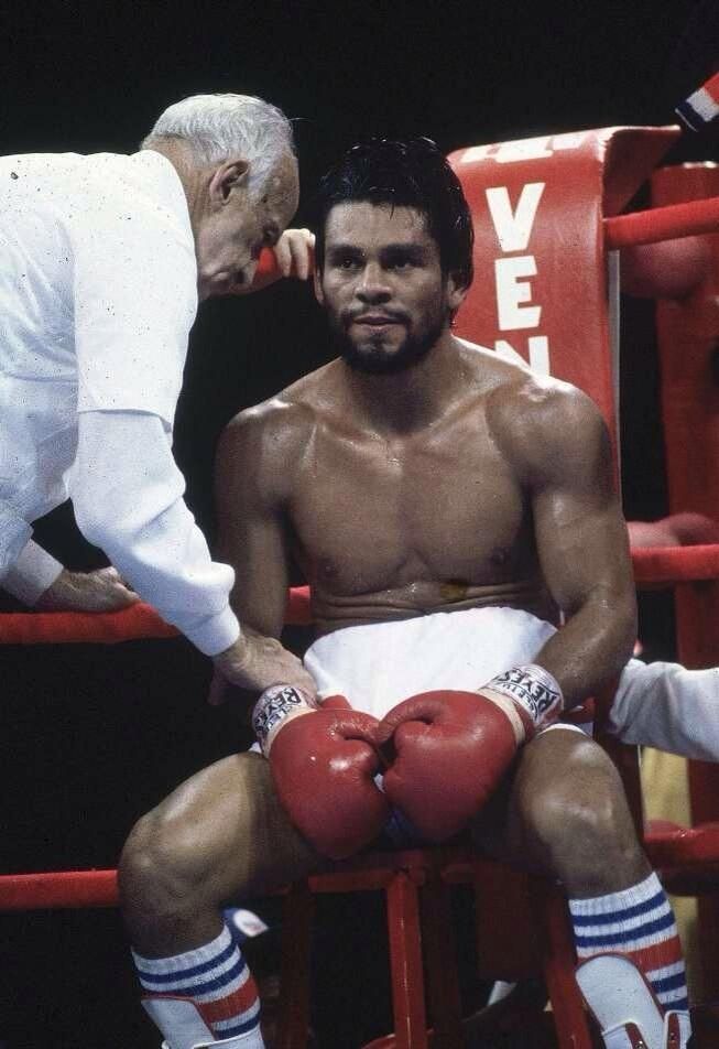 a man sitting on top of a red chair next to a boxer wearing boxing gloves