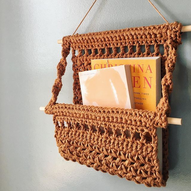 a crocheted basket hanging on the wall with a book and soap in it