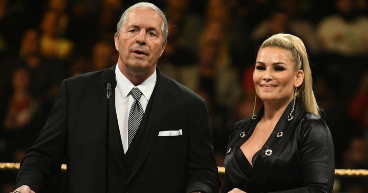 a man and woman standing next to each other in front of a crowd at a wrestling match