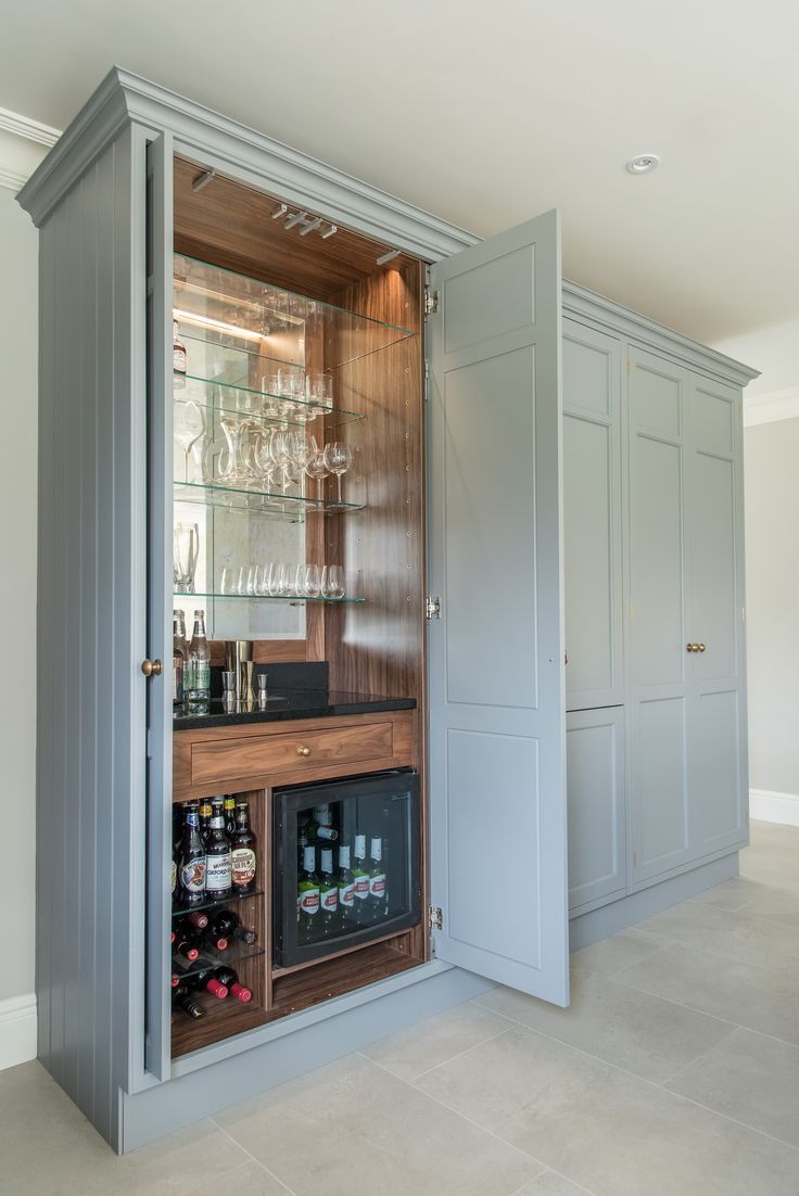 an open cabinet in the middle of a room filled with wine glasses and liquor bottles