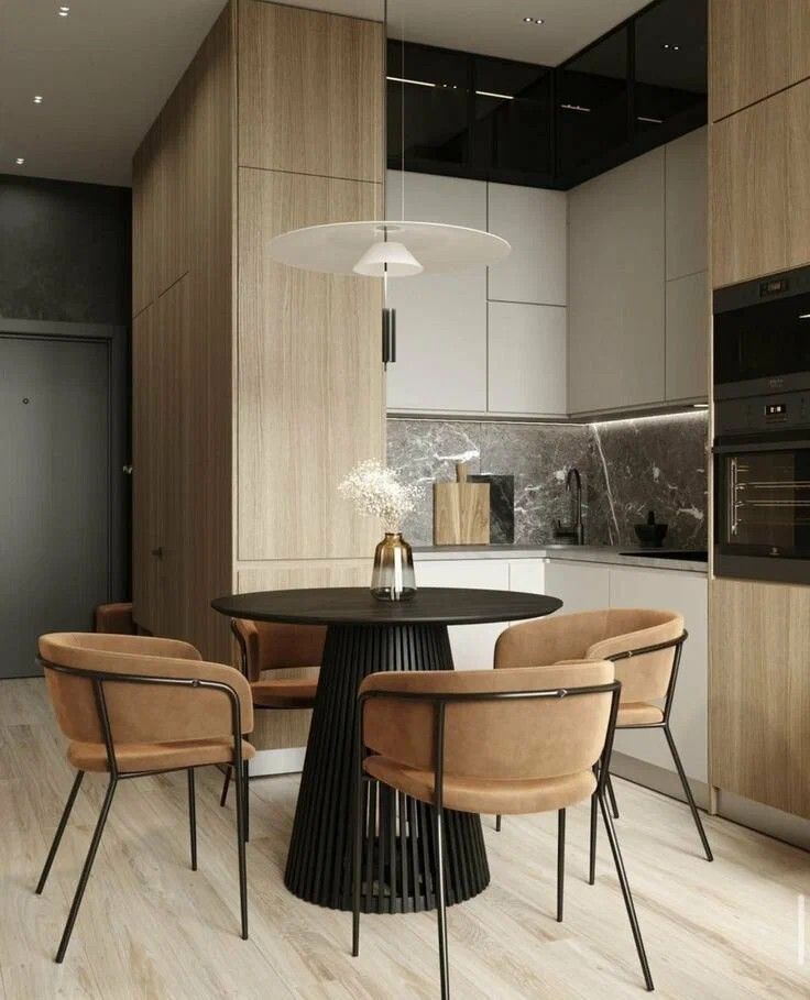 a black table and chairs in a room with white walls, wood flooring and cabinets