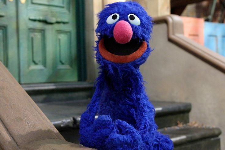 a blue stuffed animal sitting on top of a wooden table next to stairs and steps